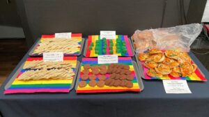 Ett bord med fem olika sorters kakor och bullar uppdukade på färgglada regnbågsservetter.